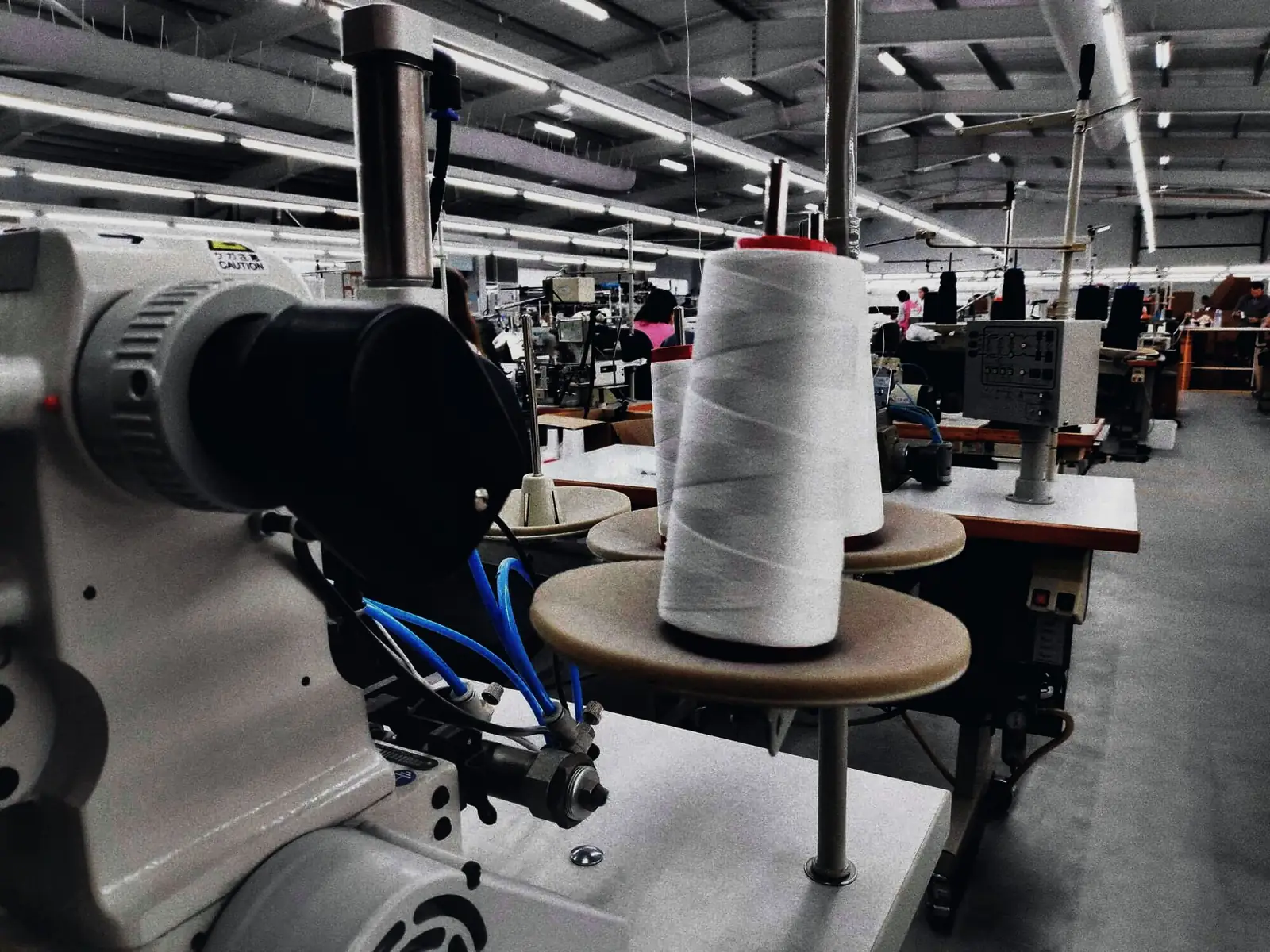 Un cono de hilo en una máquina de coser, con la sala detrás