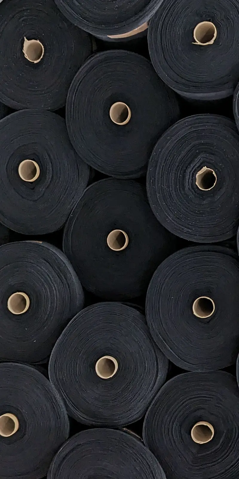 Rollos del tejido negro de algodón orgánico, vistos de canto