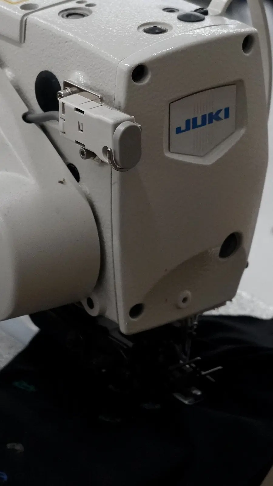 Una máquina de coser industrial Juki cosiendo un tejido negro